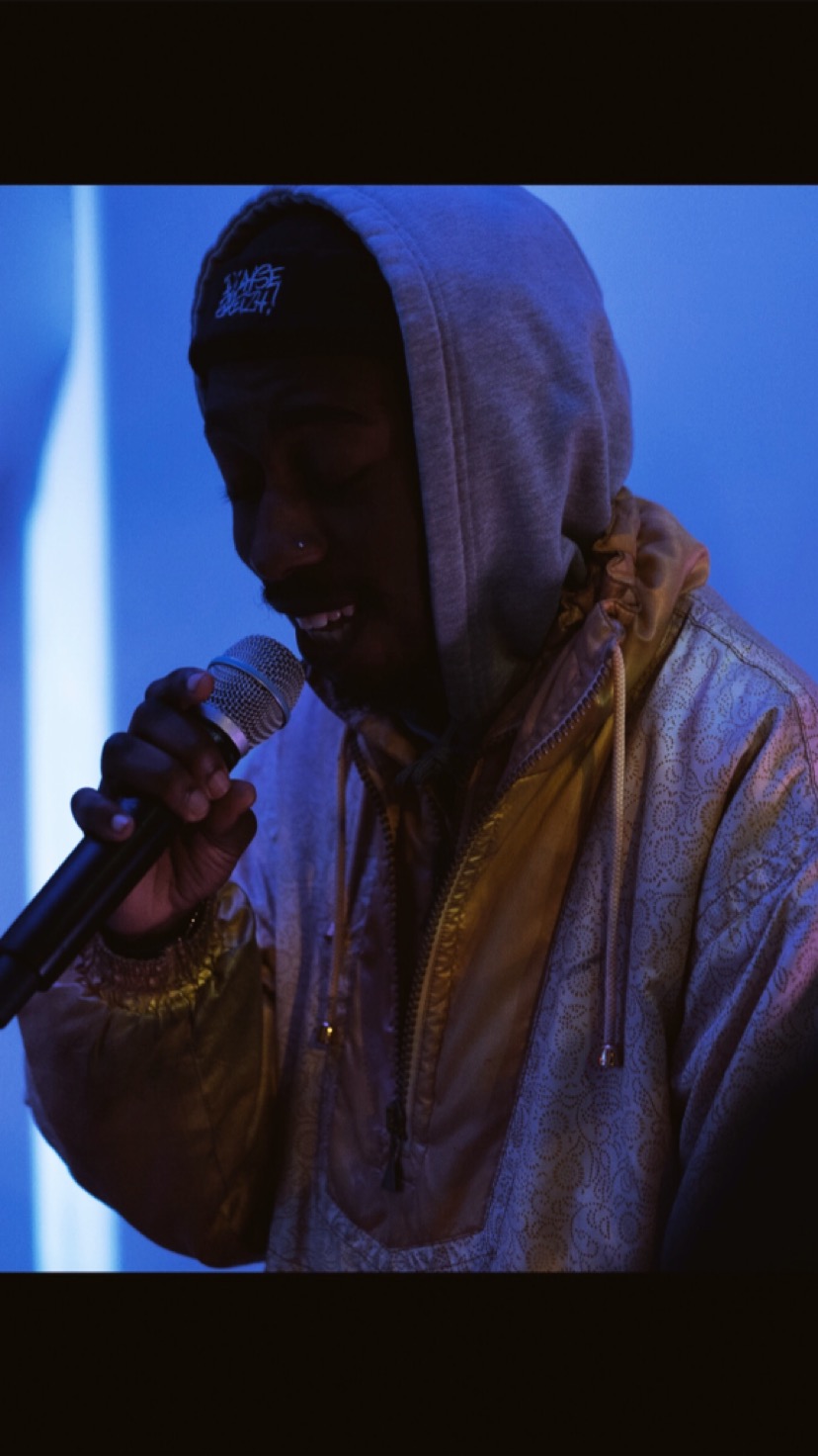 WHOKMY performing with a microphone under blue stage lighting